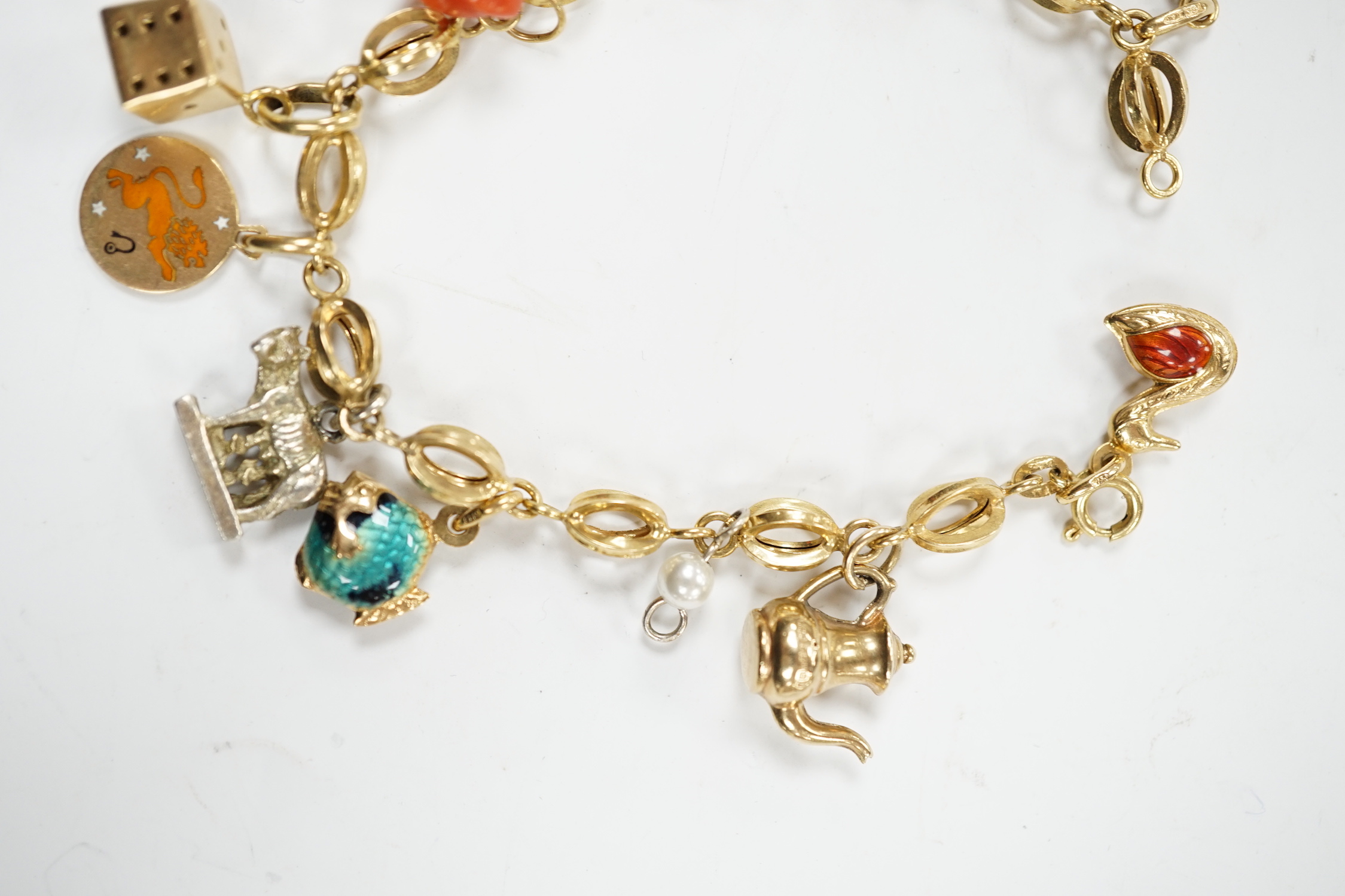 An Italian 750 charm bracelet, hung with eleven assorted charms including 9ct, yellow metal and 800 standard white metal